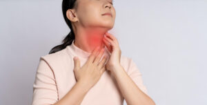 Woman touching her throat with a reddened neck, indicating throat pain or irritation mindset (sore throat).