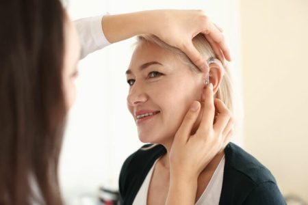 Otolaryngologist-putting-hearing-aid-inwomans-ear-Gateway-ENT-St-Louis-MO-768x512