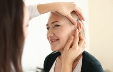 Otolaryngologist-putting-hearing-aid-inwomans-ear-Gateway-ENT-St-Louis-MO-768x512